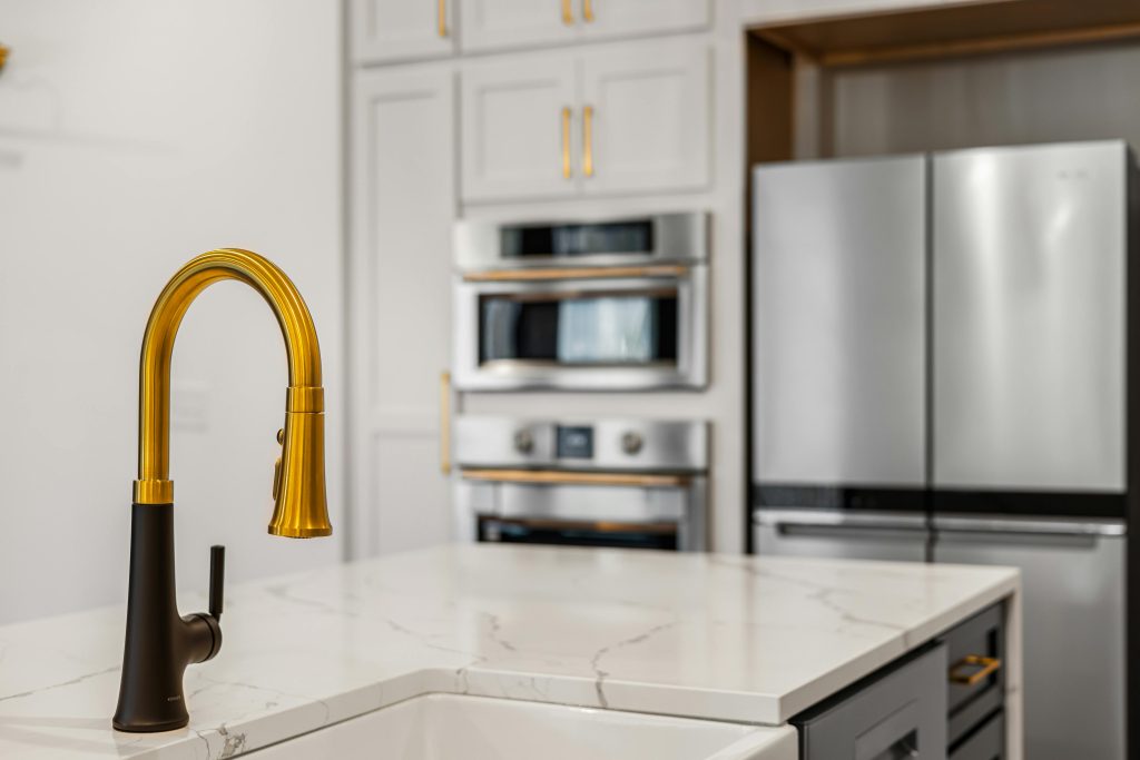 Elegant kitchen interior with a modern gold faucet and sleek stainless steel appliances. Elegant kitchen interior with a modern gold faucet and sleek stainless steel appliances.
